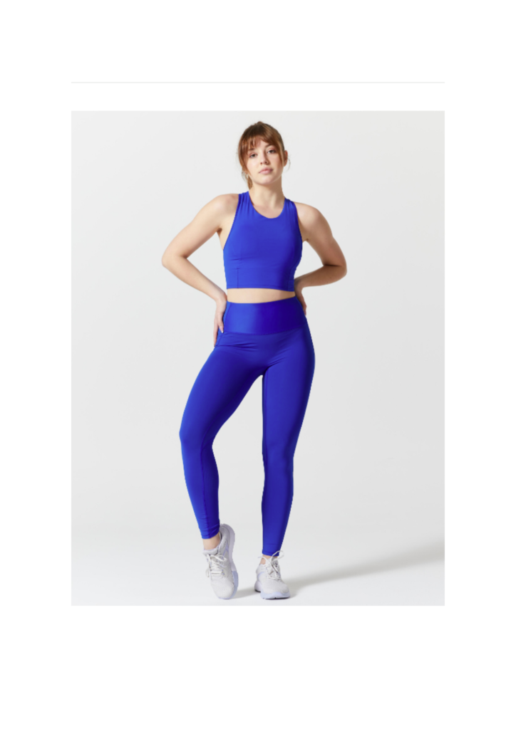 Dona amb un conjunt de roba esportiva de color blau electric amb una actitud postiva i motivadora.