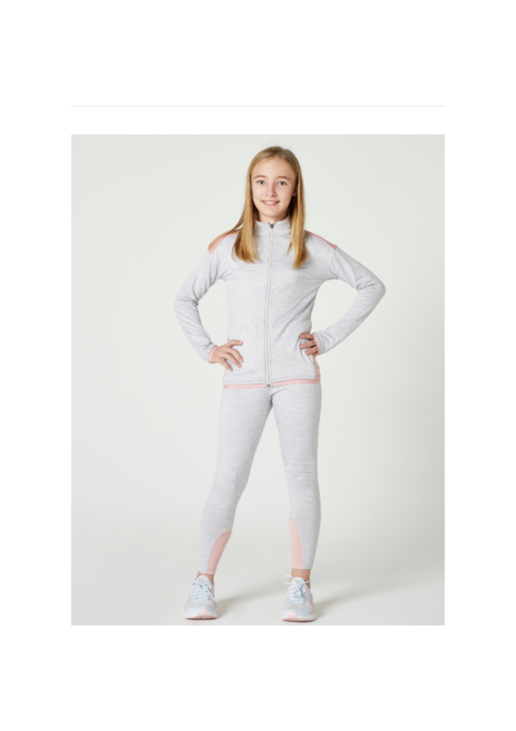 Nena petita modelant un conjunt esportiva blanc de la marca gisports posant amb un somriure